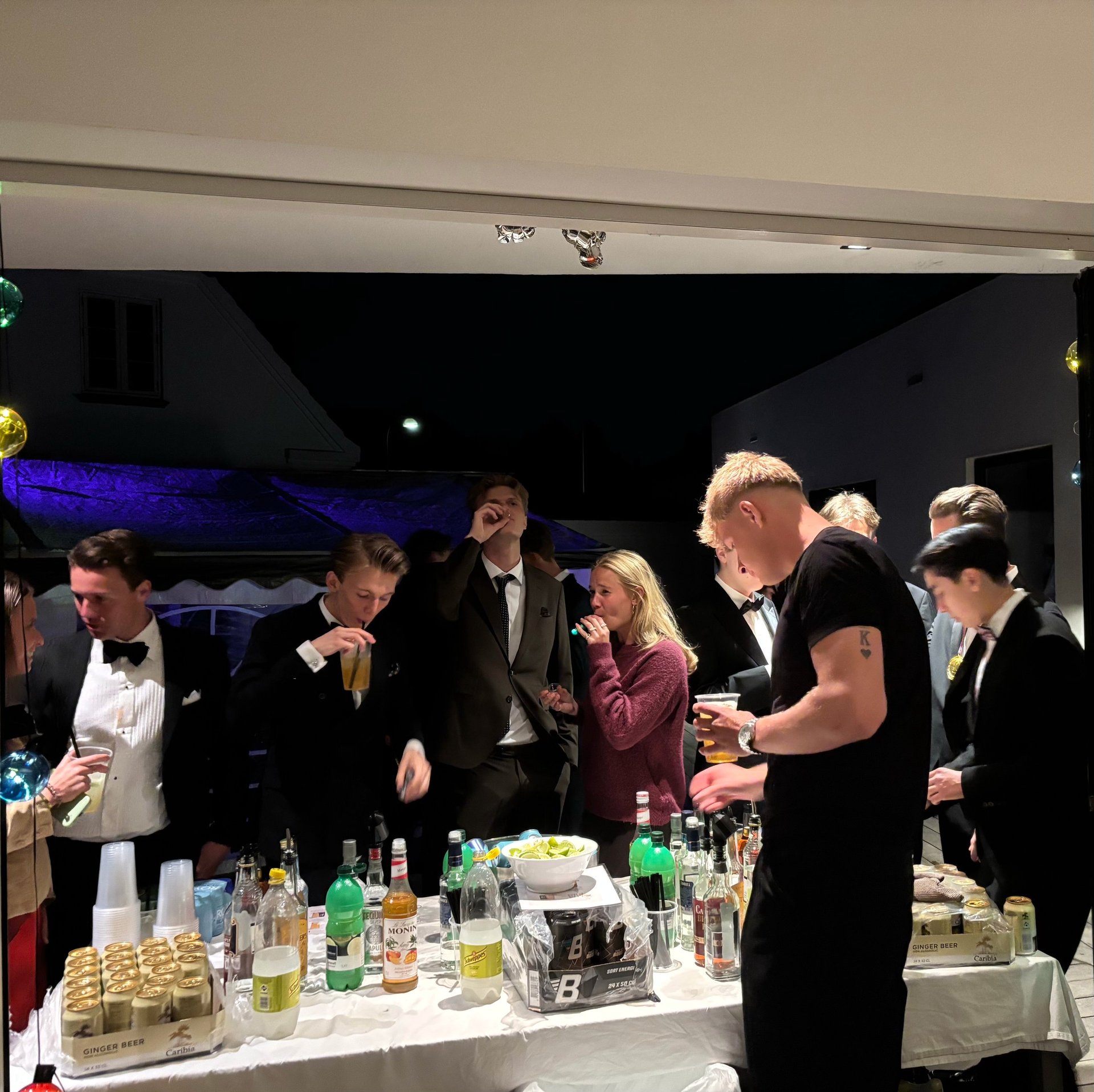 Formelt klædte gæster ved en indendørs event med bar og flasker